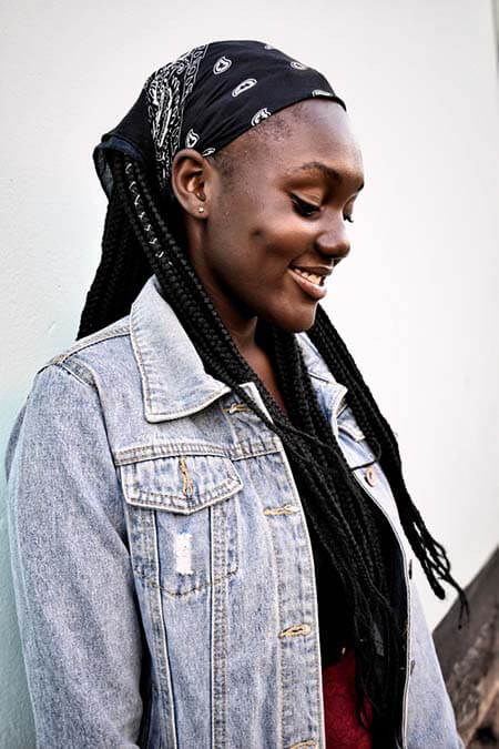 Black womxn with a professional box braids hairstyle wearing a black bandana and smiling